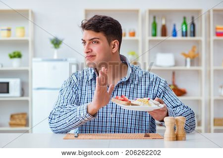 Young husband eating tasteless food at home for lunch