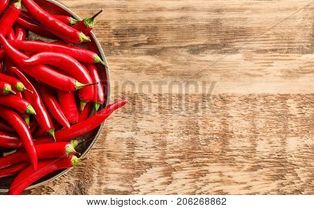 Plate with red chili peppers on wooden table