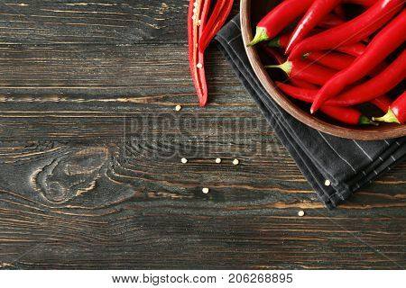 Plate with red chili peppers on wooden table