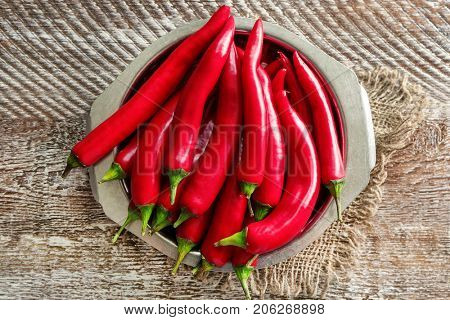 Plate with red chili peppers on wooden table