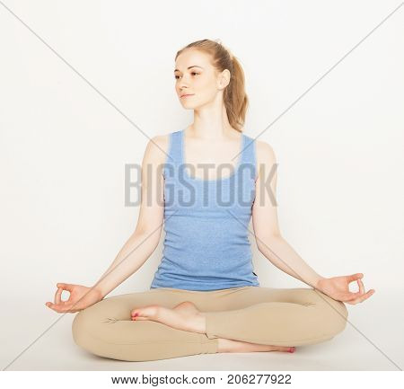lifestyle, sport  and people concept: young woman in yoga pose sitting on a floo
