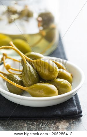 Pickled caper berries in bowl on kitchen table.