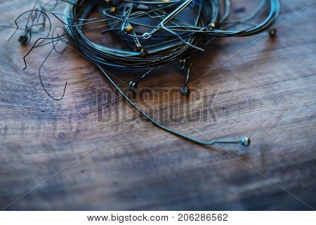 Old guitar strings, on grungy old wooden desk. Ball-end,  coiled and bundled.