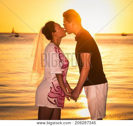 BORACAY, PHILIPHINES-MARCH 17, 2017: Asinan prime adult male groom and female bride holding hands and kissing barefoot on March 17, 2017 at Wite beach. Boacay island , Philiphines.