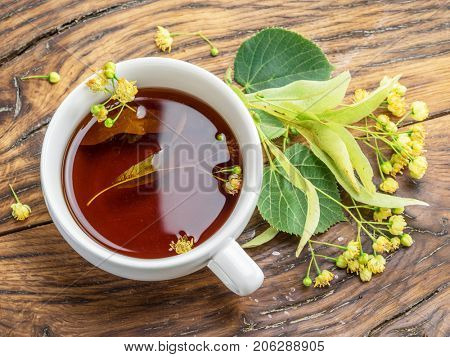 Cup of linden tea and lime flowers on the wooden table. Top view.