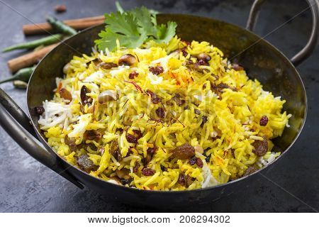 Indian vegetarian biryani with nuts and raisins as close-up in a korai 
