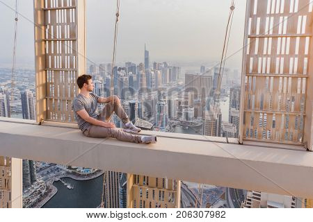 Roofer sits on concrete cross beam of Cayan Tower (Infinity Tower) in Dubai, UAE