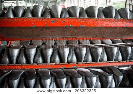 Lines of aluminum last shoes with a rough surface prepare on shelf in a shoe factory.