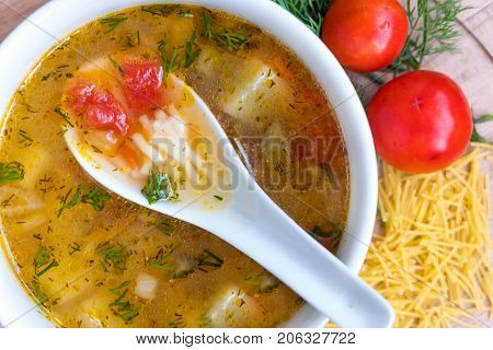 White soup noodles with tomatoes. Potatoes, dill, spices. On a wooden Board.
