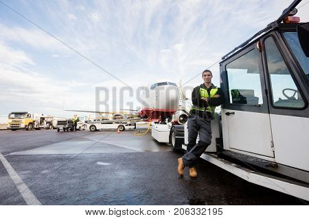 Worker Leaning On Truck With Airplane In Background