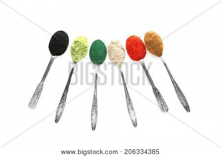 Different colorful superfood powders in spoons on white background