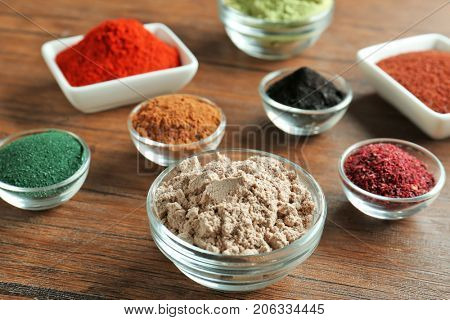 Different colorful superfood powders in bowls on wooden table