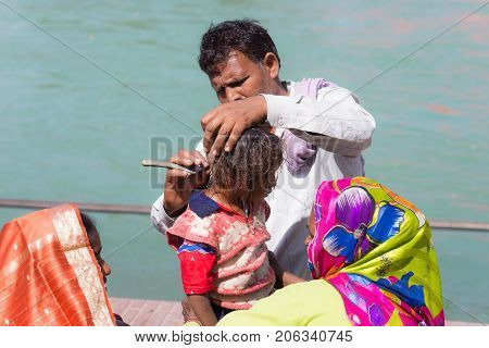 Haridwar, India - March 20, 2017: Man Shaving Off Hairs For Young Hindu Devotee Initiation On The Ga