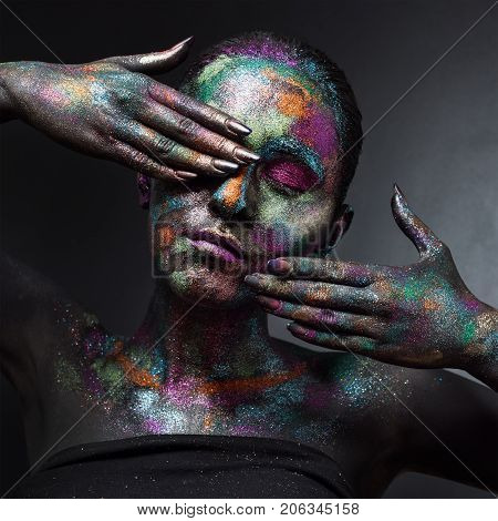 Young artistic woman in black paint and colourful powder. Glowing dark makeup. Creative body art on the theme of space and stars. Bodypainting project: art, beauty, fashion