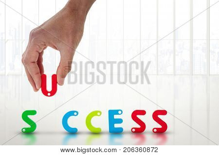 Cropped image of businessman arranging success word against white room with large window overlooking city