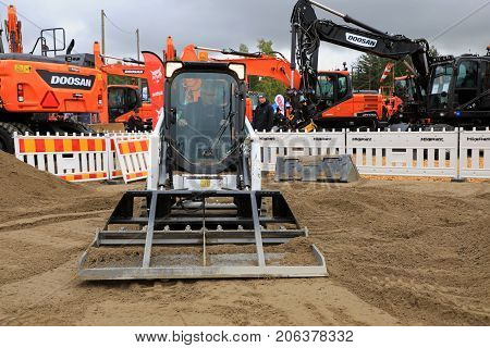HYVINKAA FINLAND - SEPTEMBER 8 2017: Operator levels ground with Bobcat T450 Compact Track Loader and landplane attachment on sand work site on Maxpo 2017.
