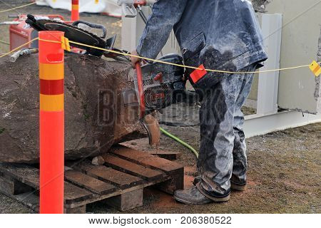 HYVINKAA FINLAND - SEPTEMBER 8 2017: Man is sawing natural granite stone with ICS Chain Saw on Maxpo 2017.