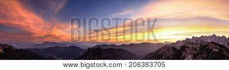 Mountain landscape panorama at sunset in Triglav National Park. Amazing view on colorful clouds and layered mountains in the evening. Colorful nature background. Adventure. Travel in Slovenia. Beautiful scenery.