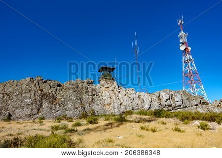 Wide angle view of fire watching hut and communication tower over big rocks