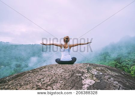 Asian women relax in the holiday. Play if yoga. On the Moutain rock cliff