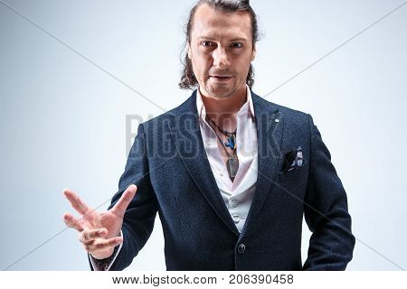 The mature bearded man in a suit holding cane. Isolated on a blue studio background.