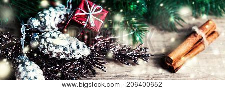 Christmas Card with Christmas gifts fir tree branches xmas holiday decorations festive symbols and falling snow on bright wooden background with copyspace