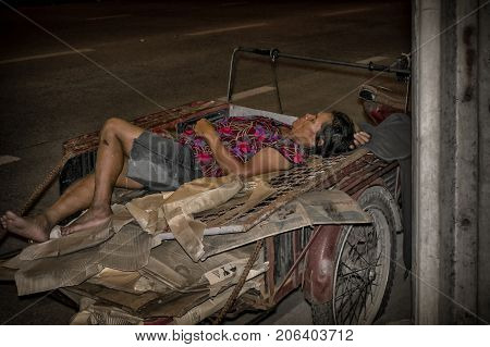BANGKOK THAILAND - AUGUST 09 - An unidentified cardboard box collector naps the cart after the rain on August 09 2017 in Bangkok.