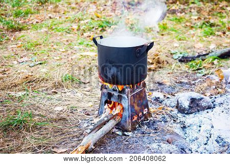 Smoked pot on a camp stove. In the saucepan is boiling
