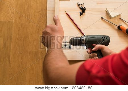 Cordless screwdriver holding by hand. Construction worker holding the hand drill. Screwdriver in the hand of the master. Carpenter working with an electric screwdriver  using a cordless screwdriver