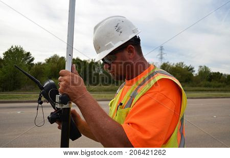 Surveyor working with equipment in hard hat and safety vest.