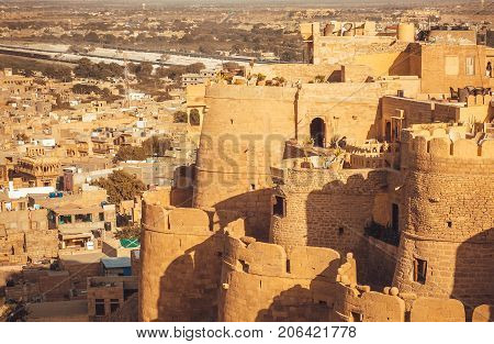Round towers of historical Jaisalmer fort with monumental stone walls over the old city in Rajasthan, India.
