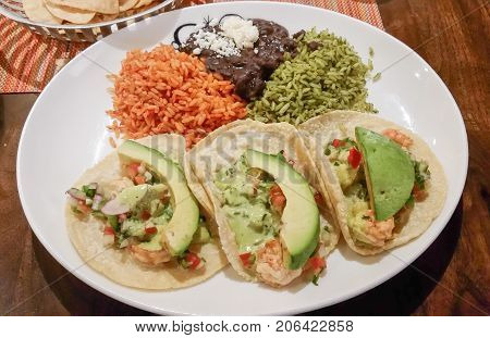 This tasty Mexican dish has shrimp tacos with avocado, two types of rice and re-fried beans