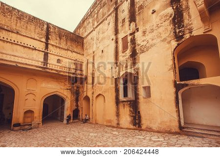 JAIPUR, INDIA - JAN 23, 2016: Grunge walls of historical Amber Fort and some tourists relaxing on January 23, 2016 in Rajasthan. Amber Fort was built in 1592 by king Raja Man Singh.