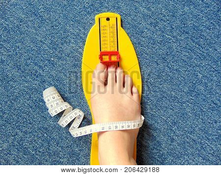 yellow foot measurement device with naked foot upon with measuring tape