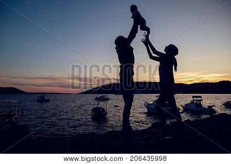 parents throw the child on the sunset at sea in Montenegro