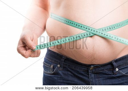 Overweight man measuring fat on his belly with green centimeter tape. Fat folds with scar closeup isolated on white background. Obesity concept