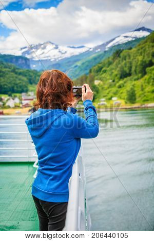 Tourism vacation and travel. Tourist woman on cruise ship enjoying fjord view taking photo with camera. Norway Scandinavia Europe. Norddalsfjorden as seen from ferry.