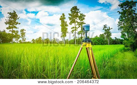 GPS surveying instrument install on tripod in green rice field Thailand