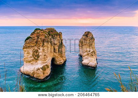 Beautiful sunset on Raouche, Pigeons' Rock. In Beirut, Lebanon.Sun and Stones are reflected in water.dense clouds in the sky.
