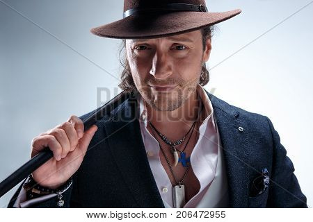 The mature bearded man in a suit and hat holding cane. Isolated on a gray studio background.