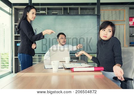 Group of Asian business people looking at businesswoman and blaming colleague for failure bad work results in business meeting room.