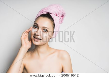 Beautiful girl with clean skin and a towel on her head and mask under eyes