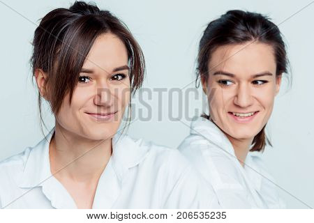 Studio portrait of young female twins sisters on gray