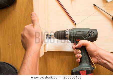 Cordless screwdriver holding by hand. Construction worker holding the hand drill. Screwdriver in the hand of the master. Carpenter working with an electric screwdriver using a cordless screwdriver