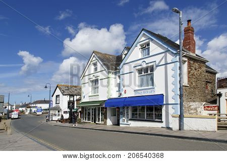 Tintagel, Cornwall, UK: April 14, 2016: Street view of the popular tourist village of Tintagel in Cornwall. There are gift shops and a pub with two people walking through the village.