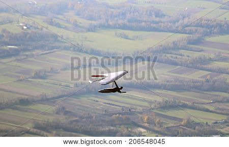 Man Flying With Hang Glider Above The Plain. This Is Extreme Spo