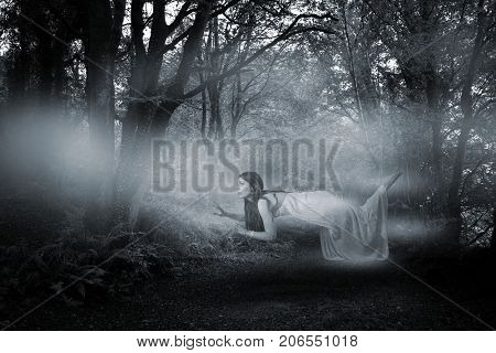 Full length of woman levitating  against way between trees