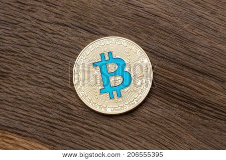 Golden cryptocurrency blue bitcoin on wooden background, close up. High resolution photo.