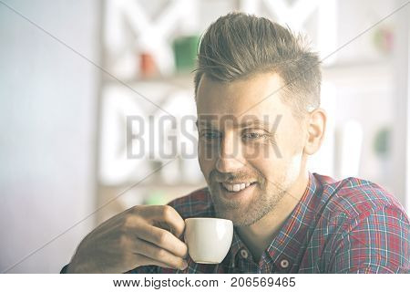 Close up portrait of attractive smiling man in casual shirt with coffee cup
