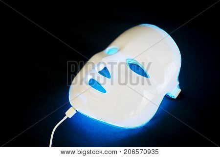 Light rejuvenating mask for facial skin therapy on black background